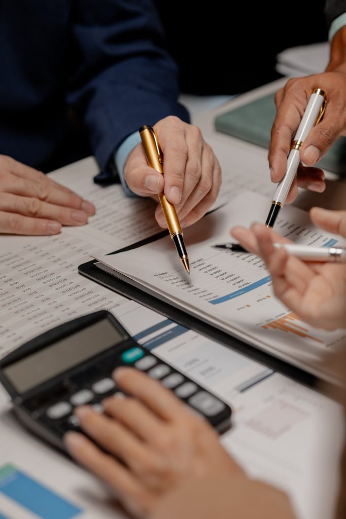 A group of three businesspeople are working together to calculat