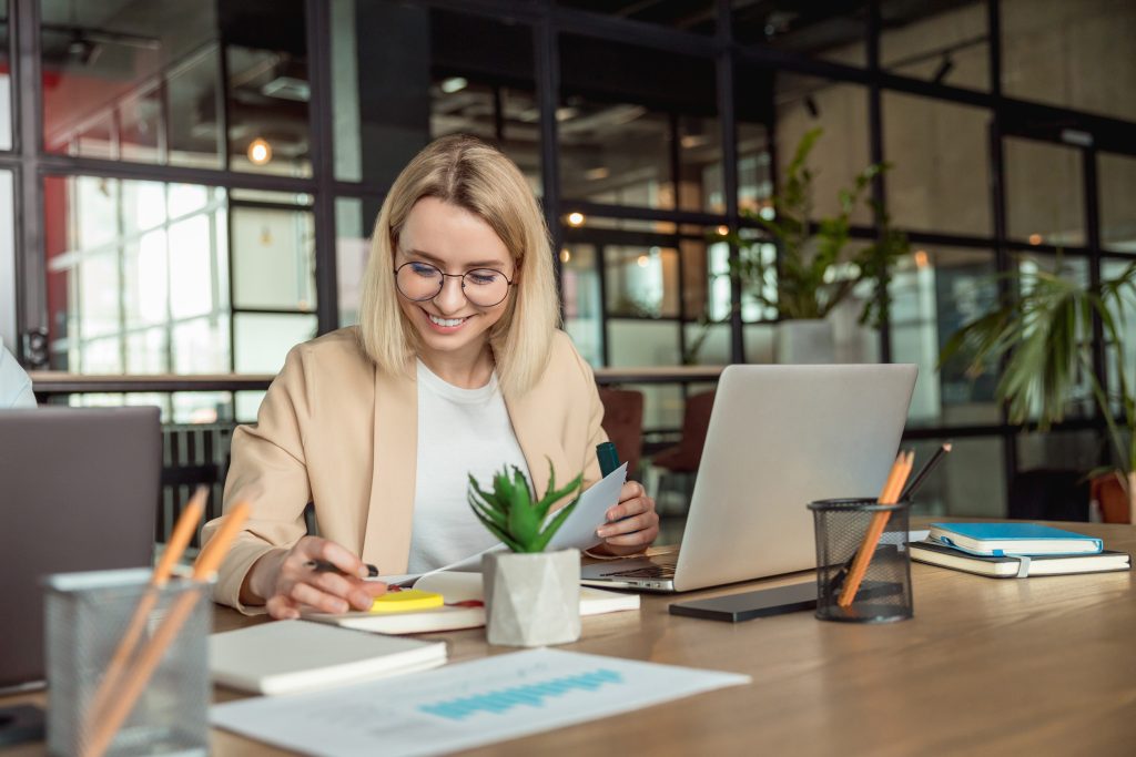 Blonde smiling young woman working in the office and looking busy